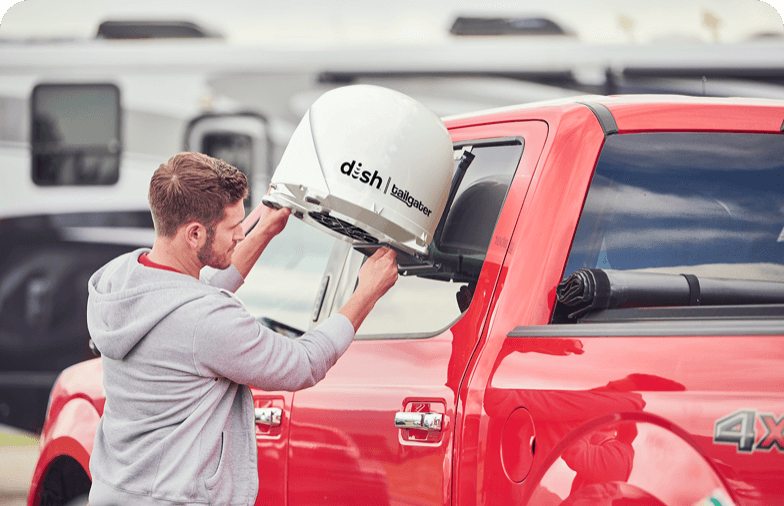 Person in gray hoodie connecting DISH Tailgater® to red truck.
                        